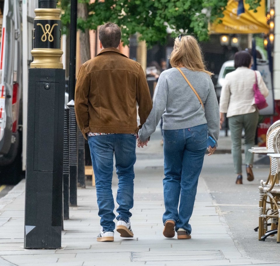 Alfie Boe and his girlfriend holding hands and walking down the street.