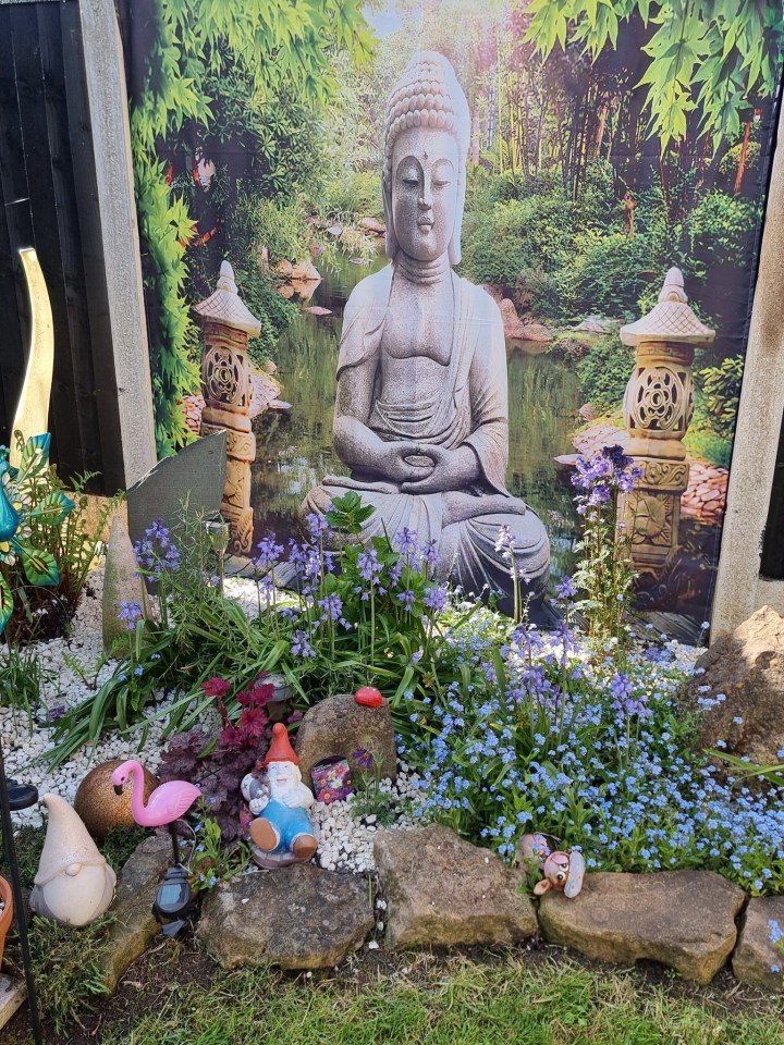 Garden with a Buddha statue backdrop and garden gnomes.