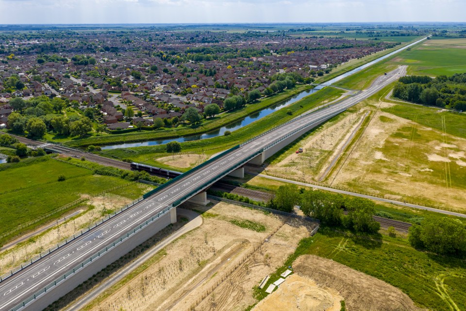 Aerial view of an unfinished bridge and road over a canal and railway.