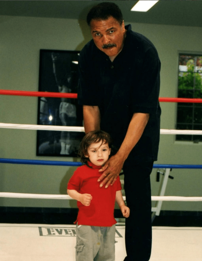 Muhammad Ali with a young child in a boxing ring.
