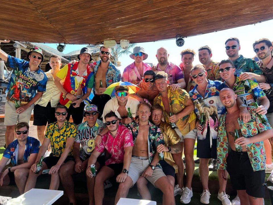 Large group of men posing for a photo, wearing colorful shirts.