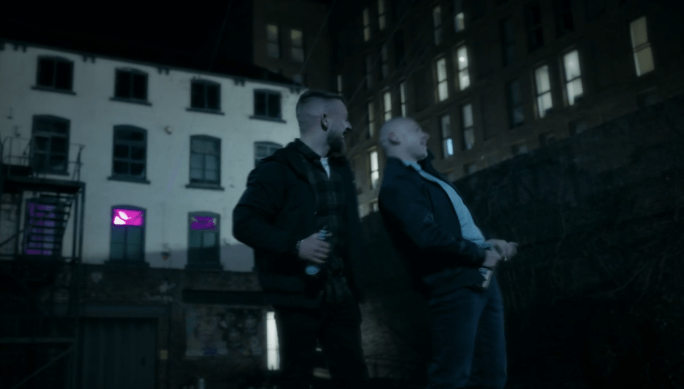 Two men laughing at night in an alleyway.