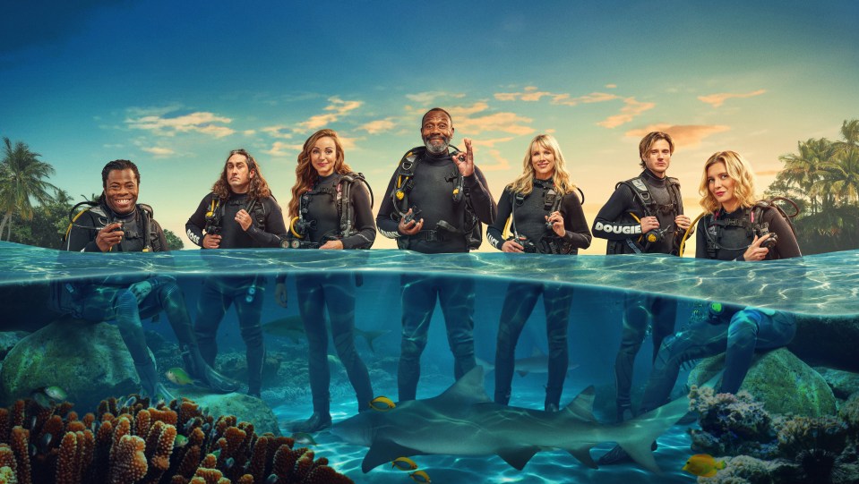 Seven celebrities in scuba gear with sharks underwater.