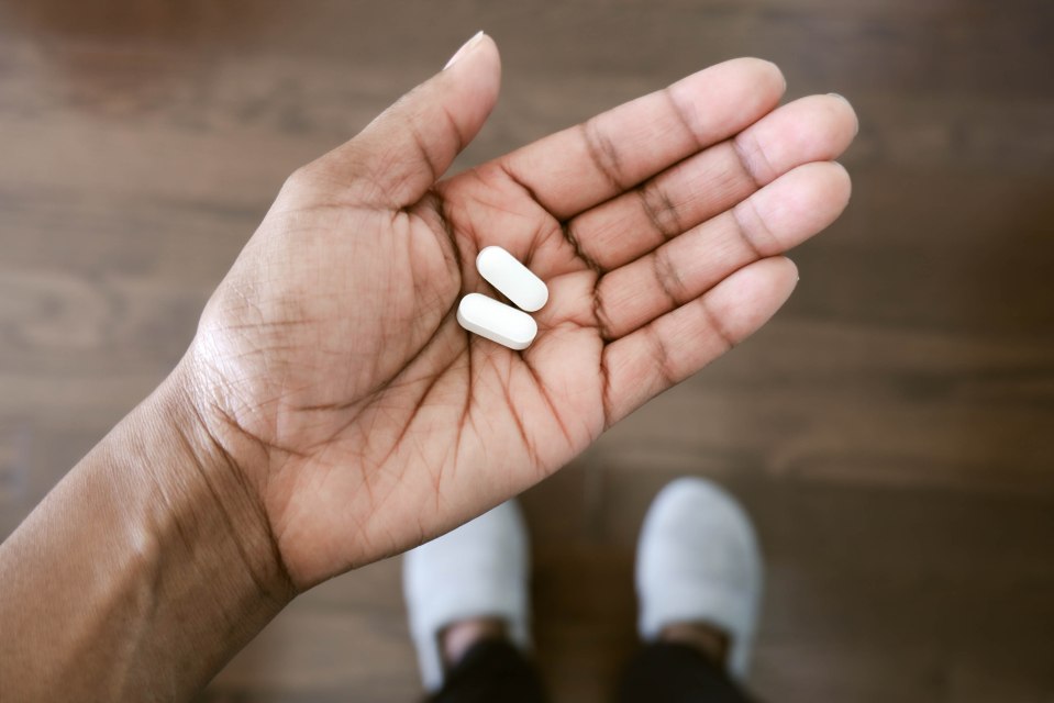 Close-up of a hand holding two pills.