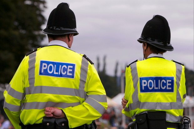 Two British police officers in uniform stand guard.