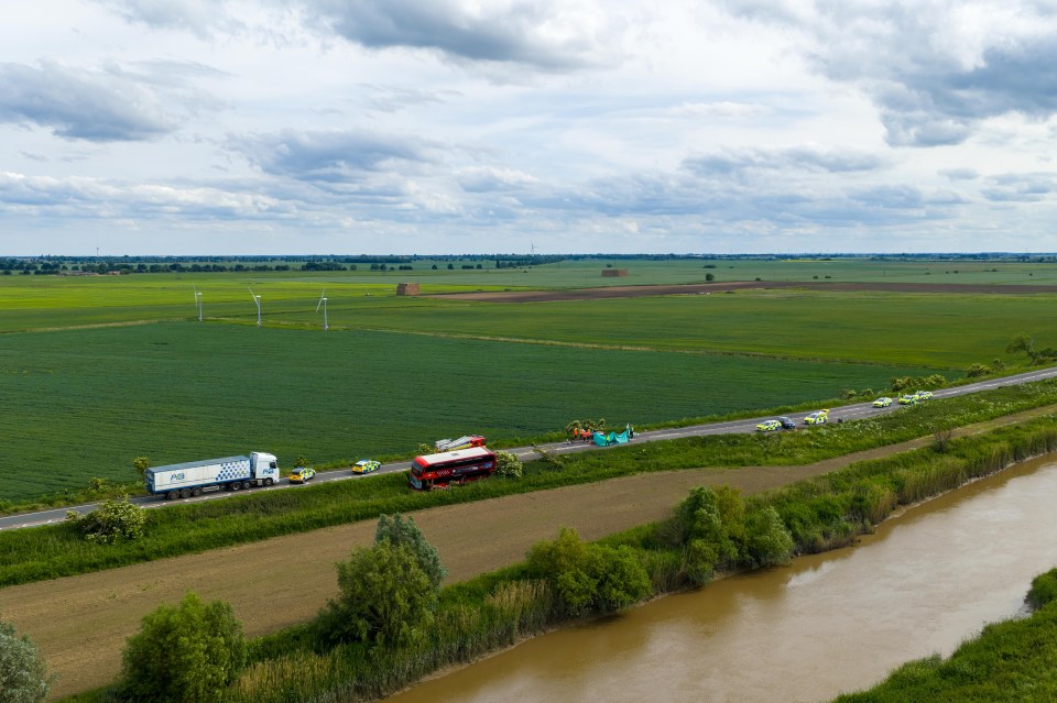 Aerial view of a double-decker bus and car accident on a rural road.