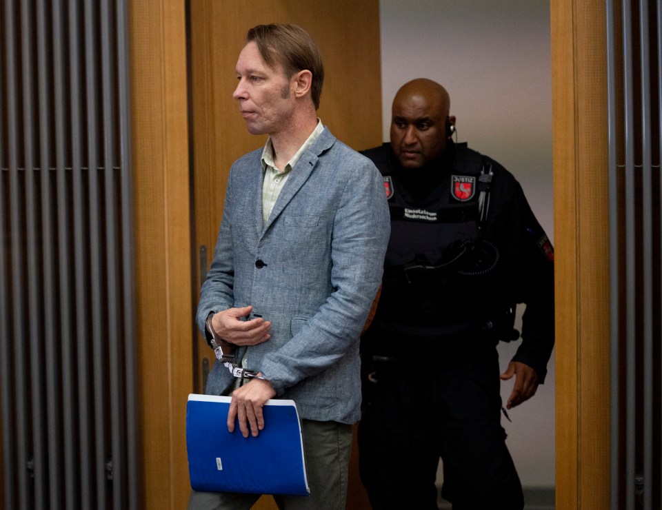 A handcuffed man escorted by a security guard.
