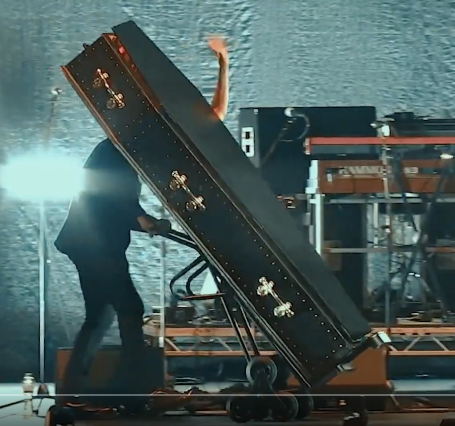 Iggy Pop being wheeled off stage in a coffin.