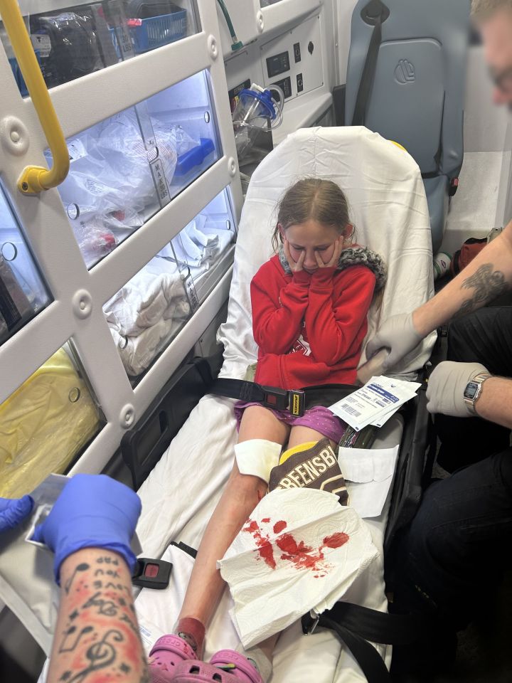 Injured girl in ambulance with leg wound.