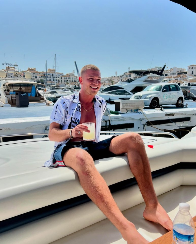 Man sitting on a boat, holding a drink.