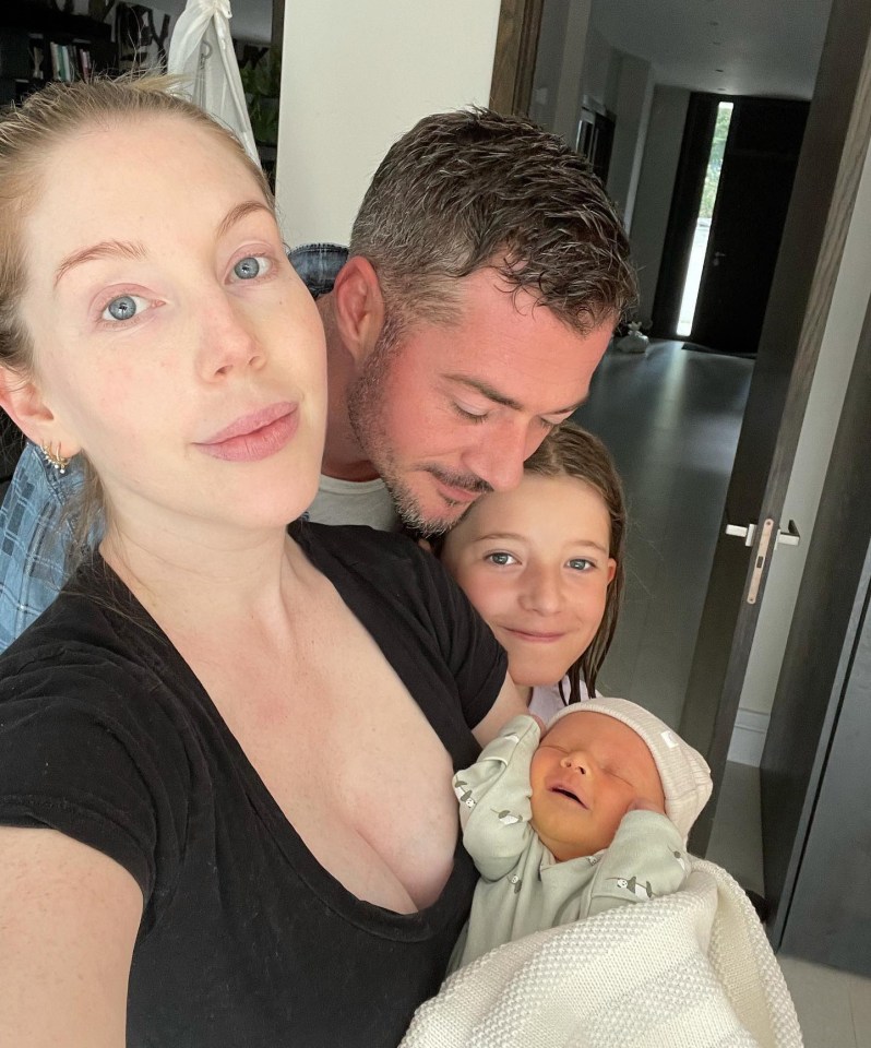 Family photo of a woman, man, girl, and newborn baby.