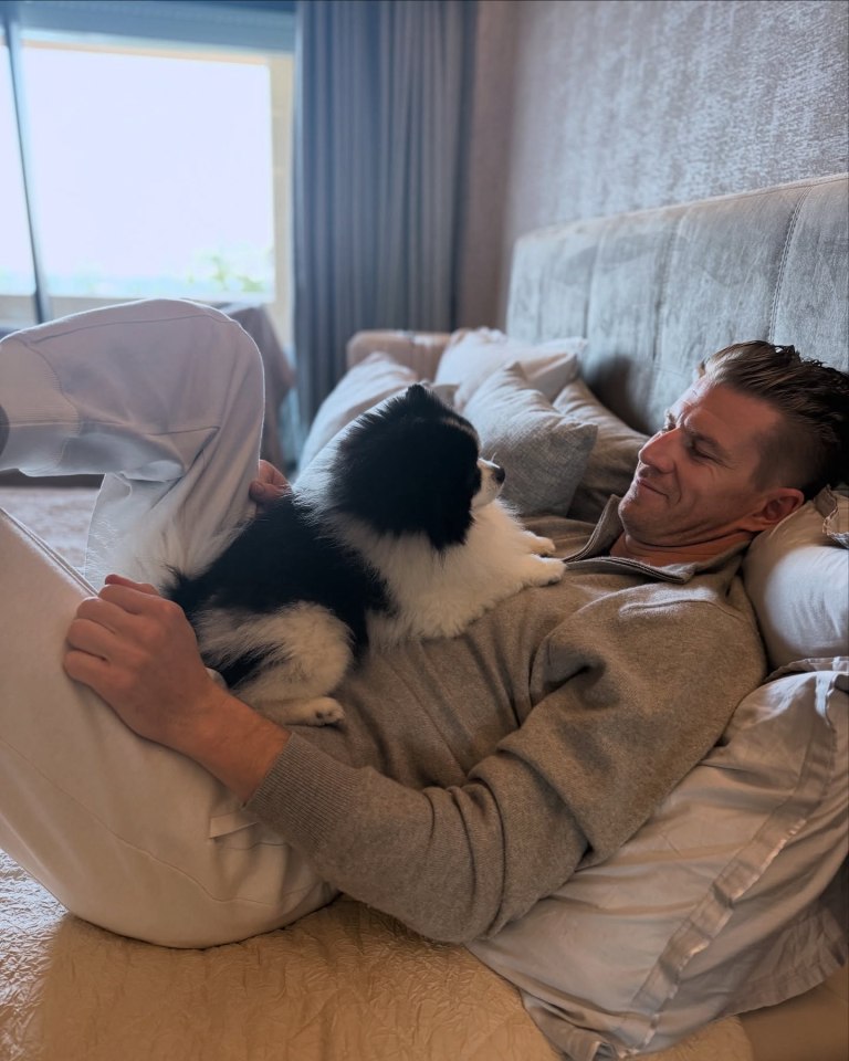Man lying in bed cuddling his dog.
